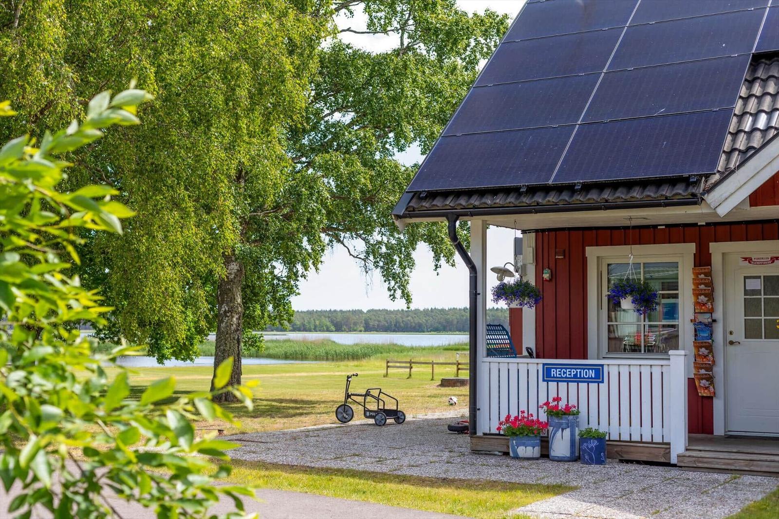 Rezeptionshaus mit Solarpaneelen und Blick auf einen See.