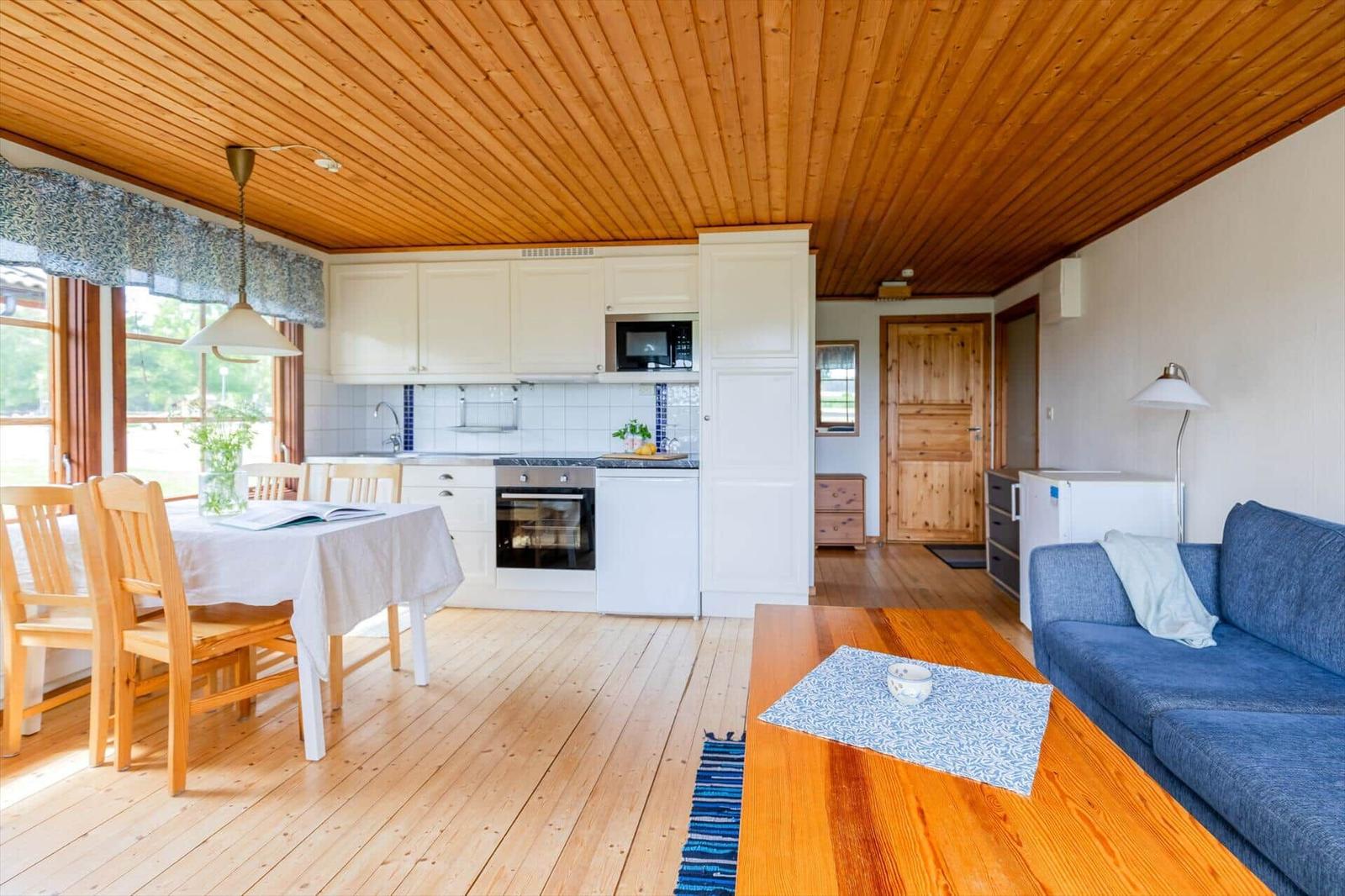 Wohnküche mit Holzboden, blauem Sofa und Essbereich mit Tisch und Stühlen.