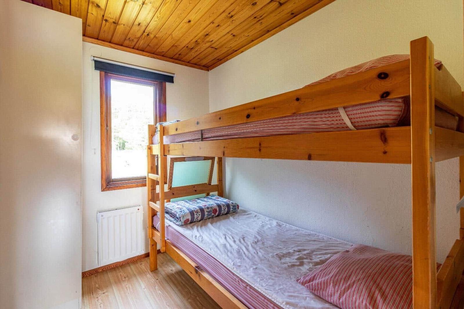 Ein Schlafzimmer mit einem Holzbett und einem Fenster.