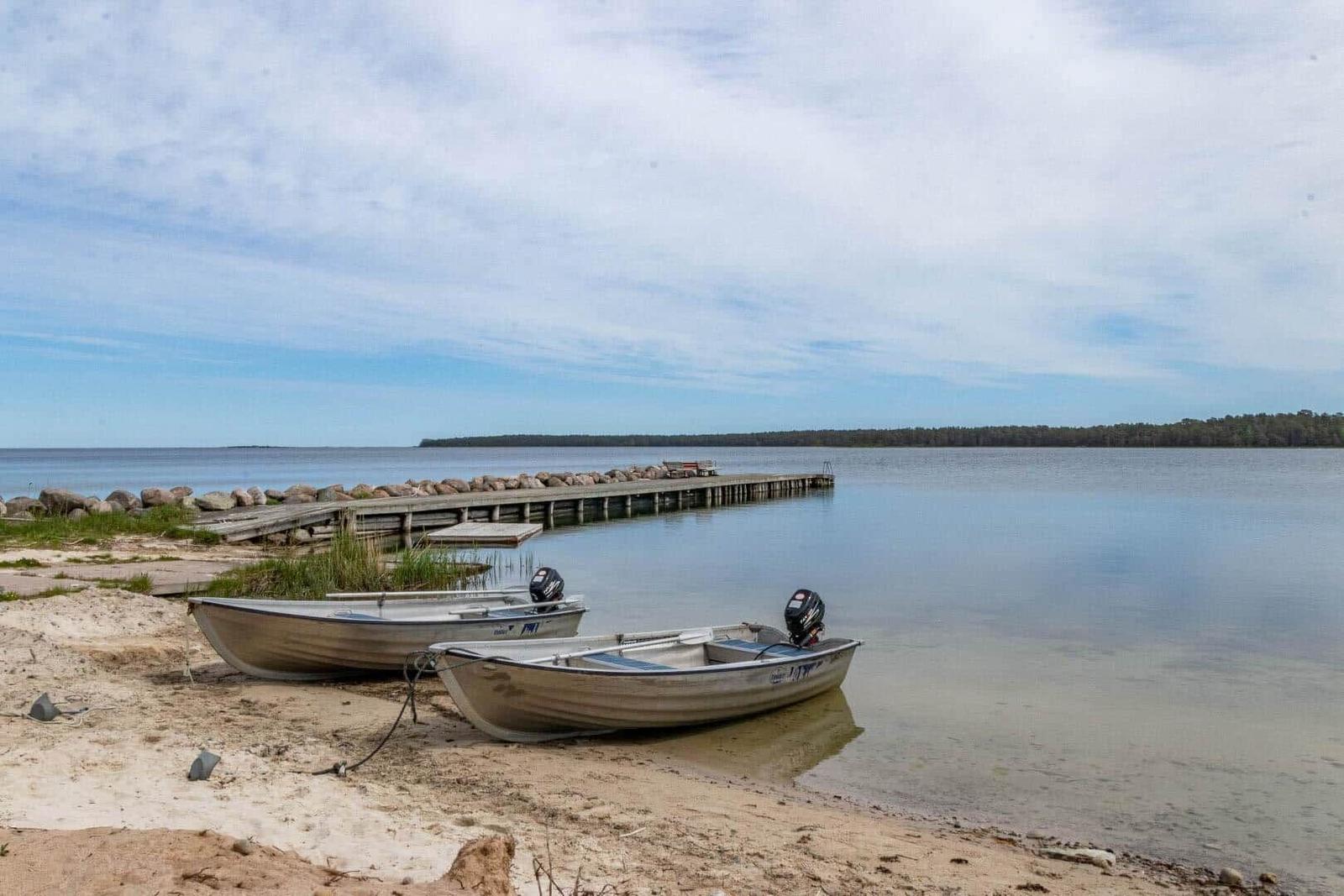 Zwei Motorboote liegen am Strand vor einer Holzbrücke.