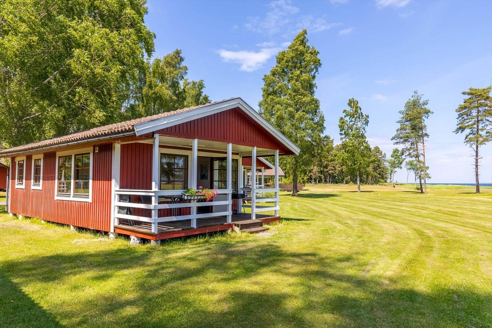 Rotes Holzhaus mit Veranda und Garten. Blick auf den See.