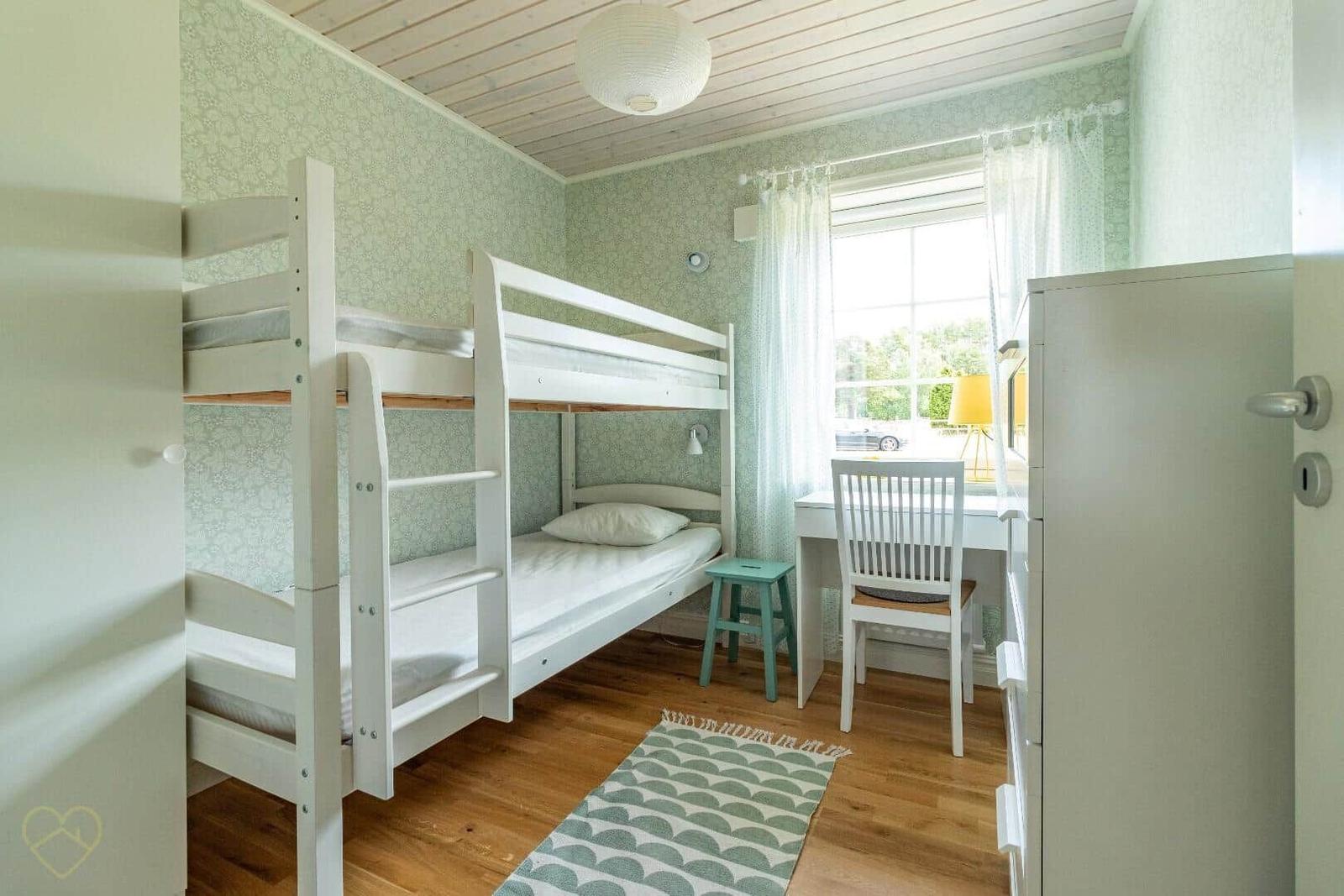 Zimmer mit Doppelstockbett, Schreibtisch und Holzboden.