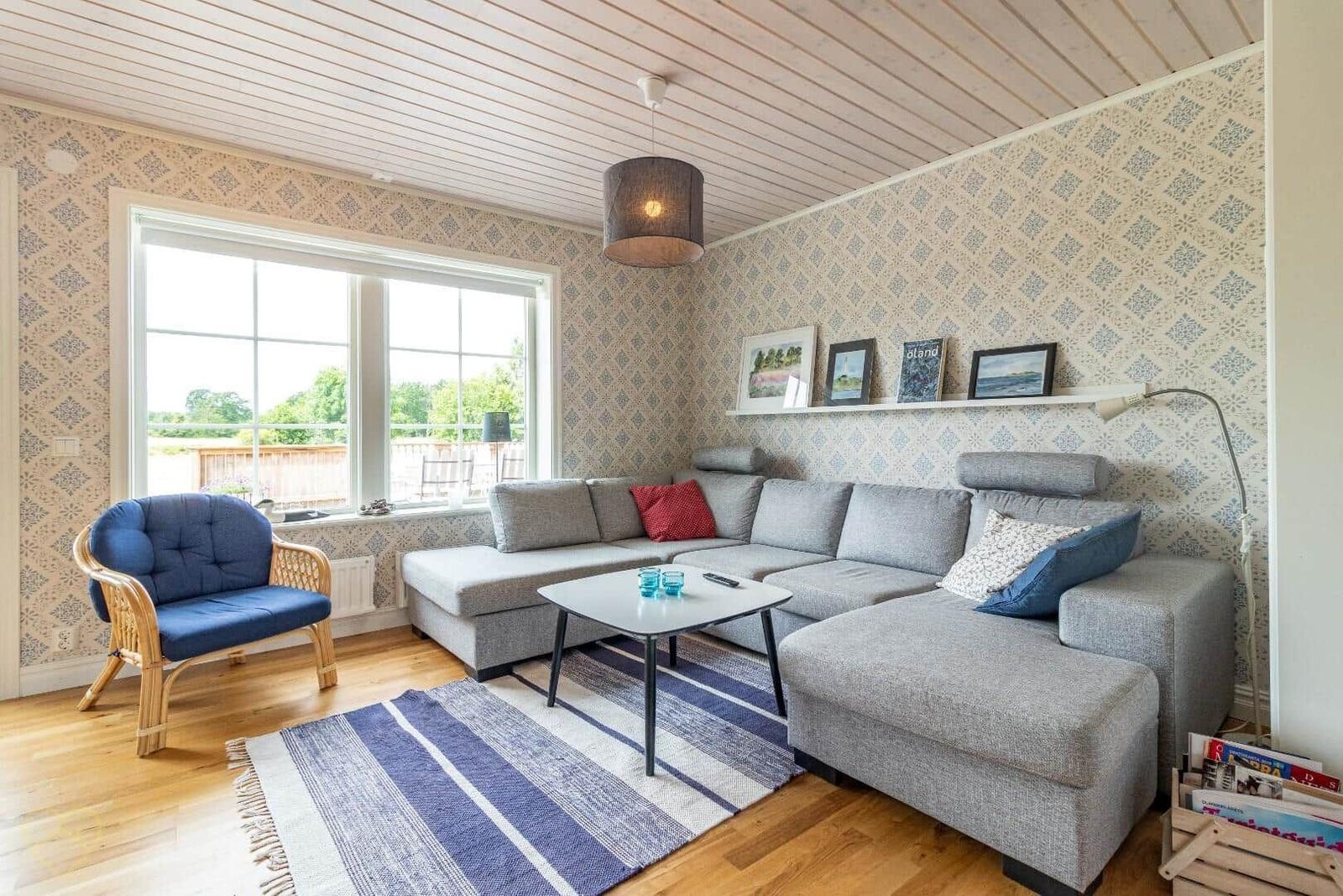 Wohnzimmer mit grauem Sofa, blauem Sessel und gemusterten Wänden.