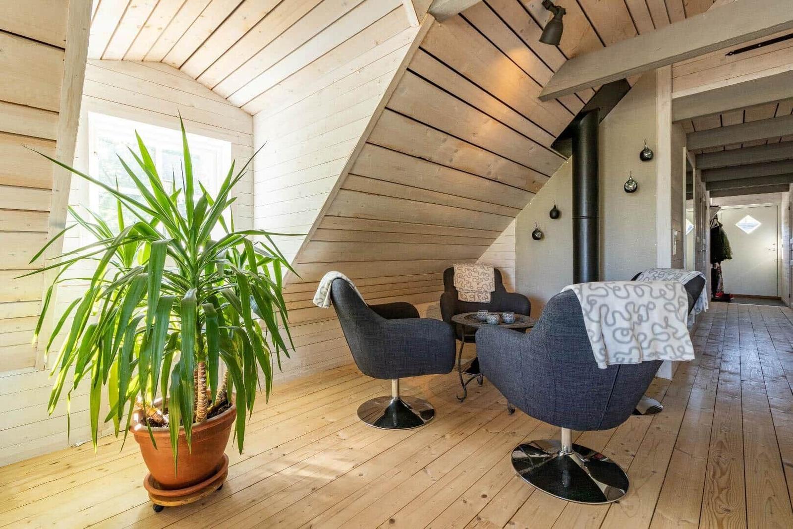 Wohnbereich mit Sitzgruppe, Pflanze und Holzwand. Holzdecke und Boden.
