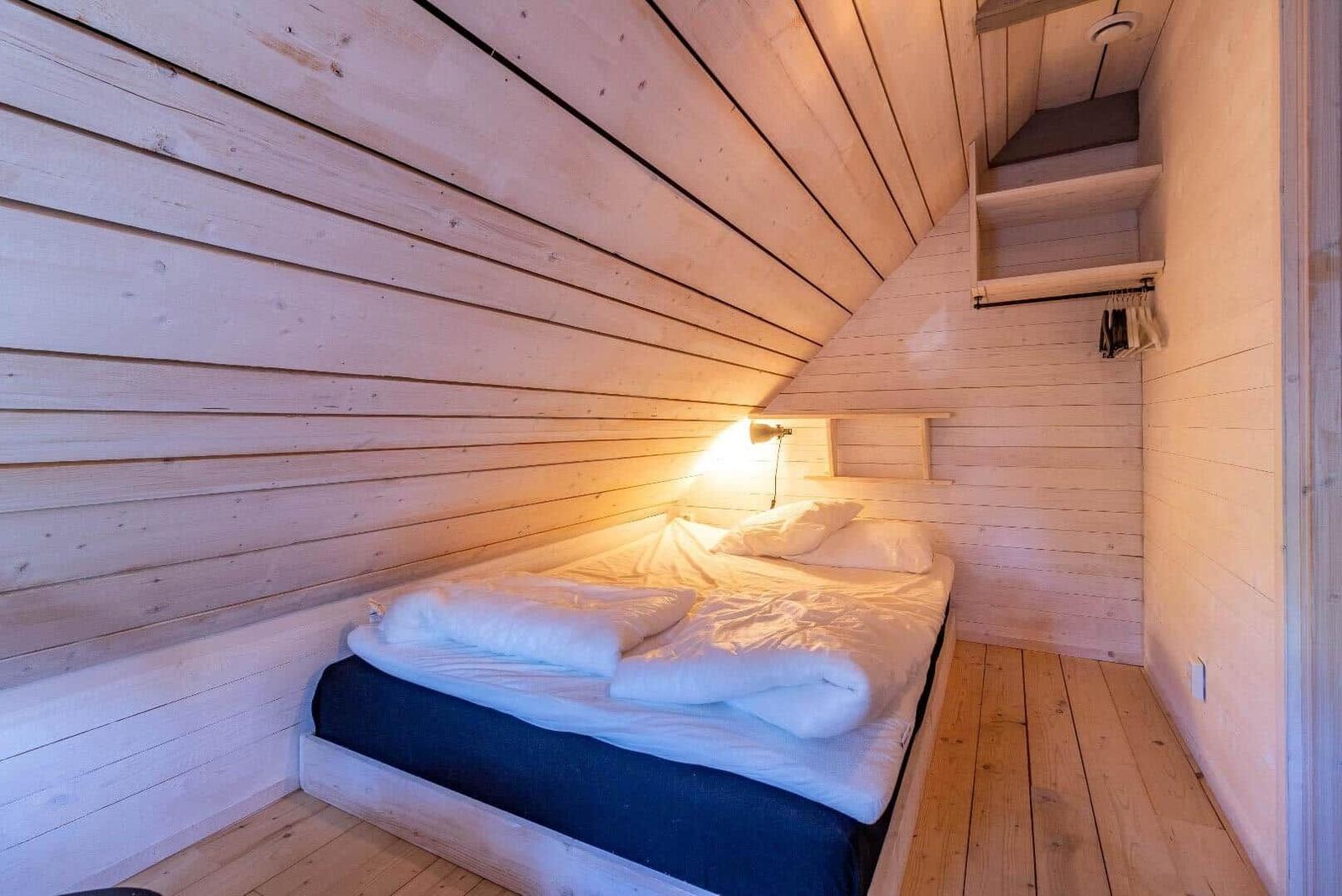 Schlafzimmer mit Holzwand, Bett und Kleiderständer