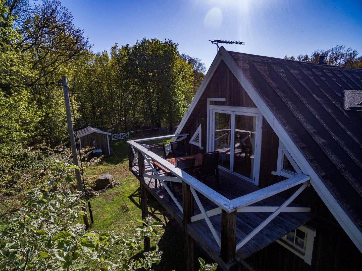 Holzhütte mit Balkon, umgeben von Wald und Grünfläche.