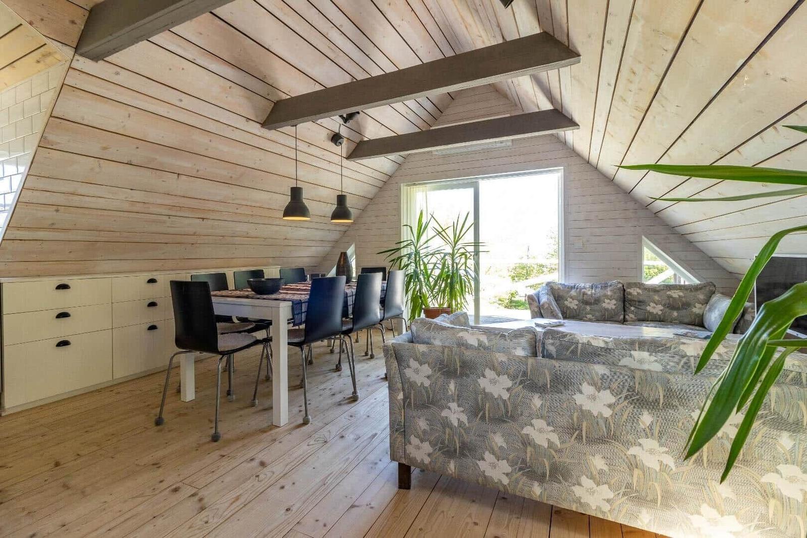 Wohn- und Essbereich mit Holzdecke, Sofa und Esstisch.