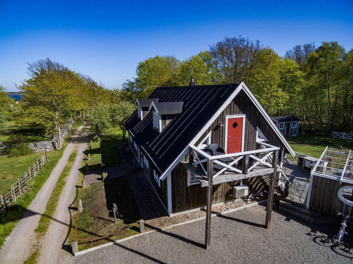 Holzhäuschen mit roter Tür, Terrasse und Garten. Blick auf Wald und See.