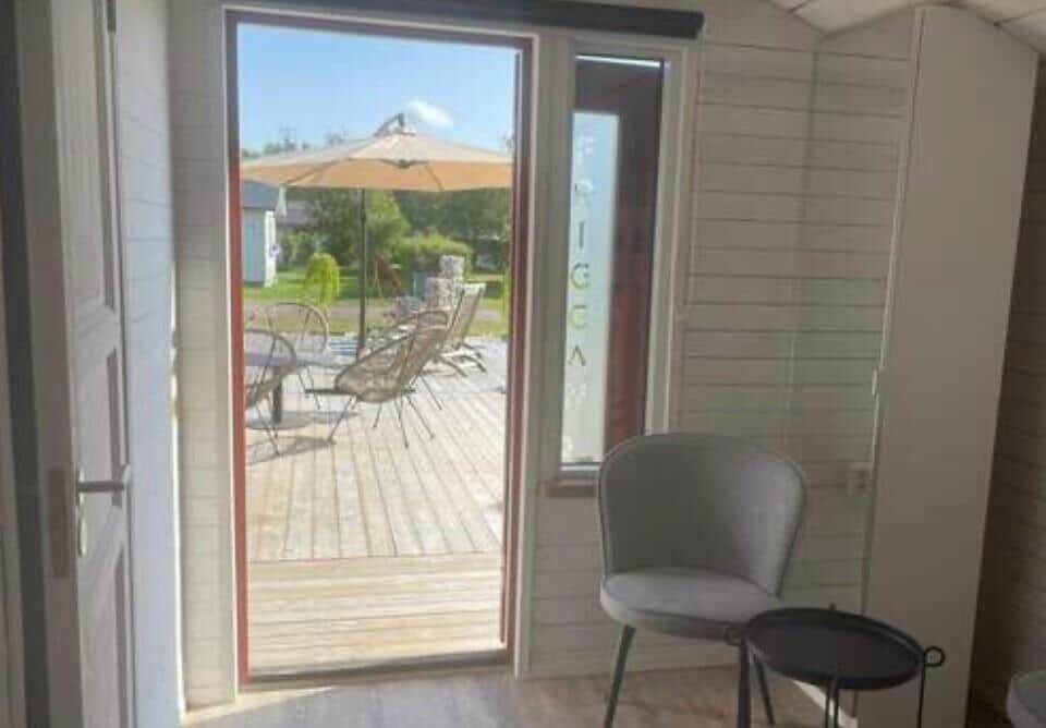 Durch die Glastür führt ein Blick auf die Terrasse mit Sonnenschirm und Sitzgelegenheiten.