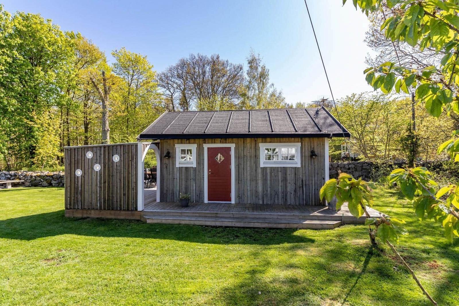 Holzhütte mit roter Tür und Terrasse im grünen Garten