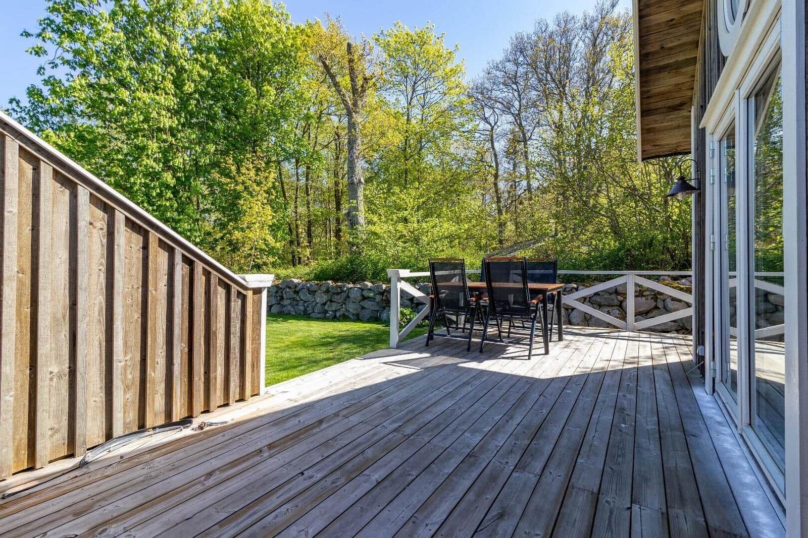Holzterrasse mit Sitzgruppe, Blick auf grünen Rasen und Wald.