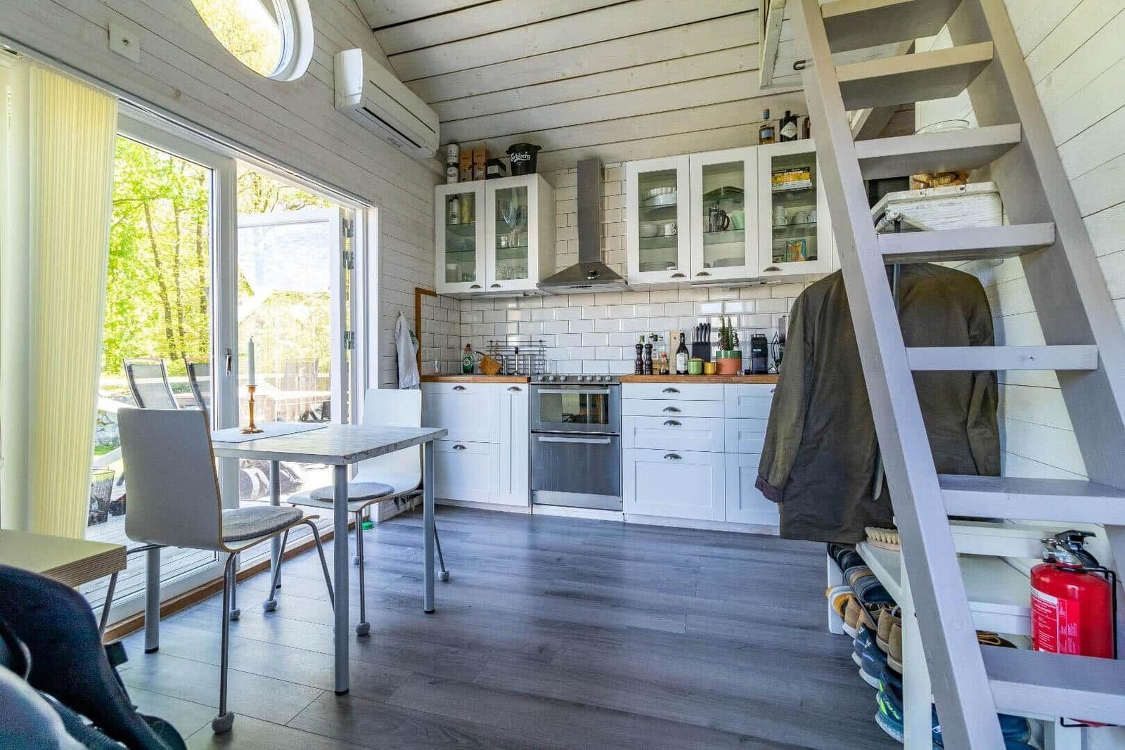 Küche mit Essbereich, Fenster, Kamin und Treppe zur oberen Etage.