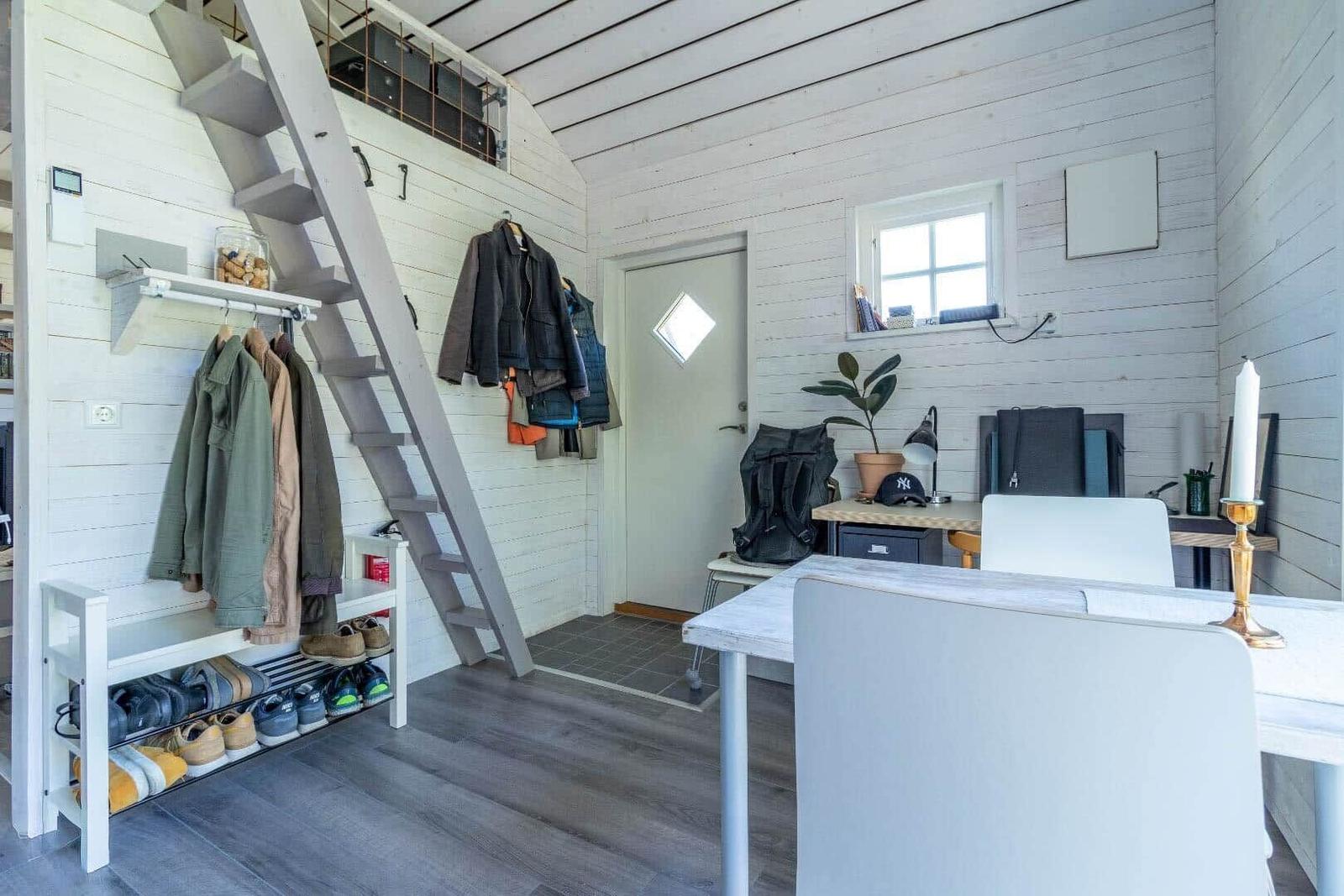 Raum mit Treppe, Kleiderständer, Schuhschrank und Tisch mit Stühlen.