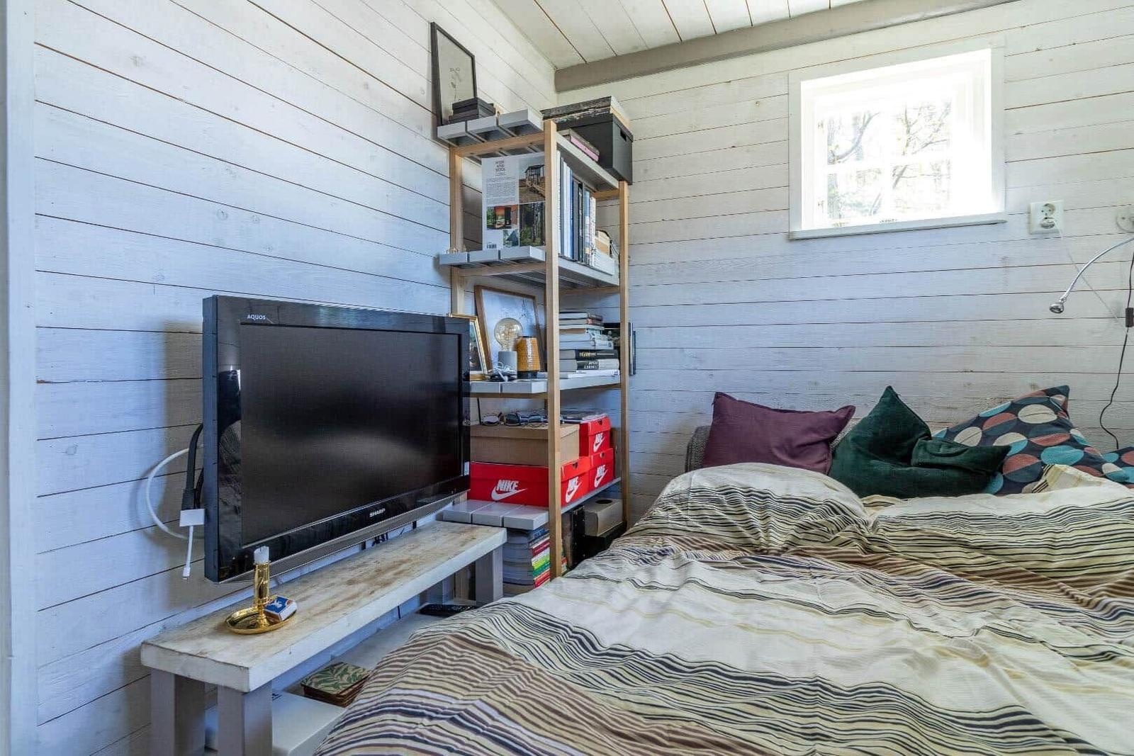 Schlafzimmer mit Bett, Fernseher und Bücherregal an der Wand.