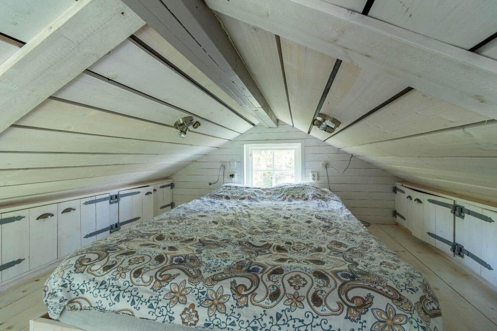 Schlafzimmer mit Dachschrägen, Bett und Fenster.