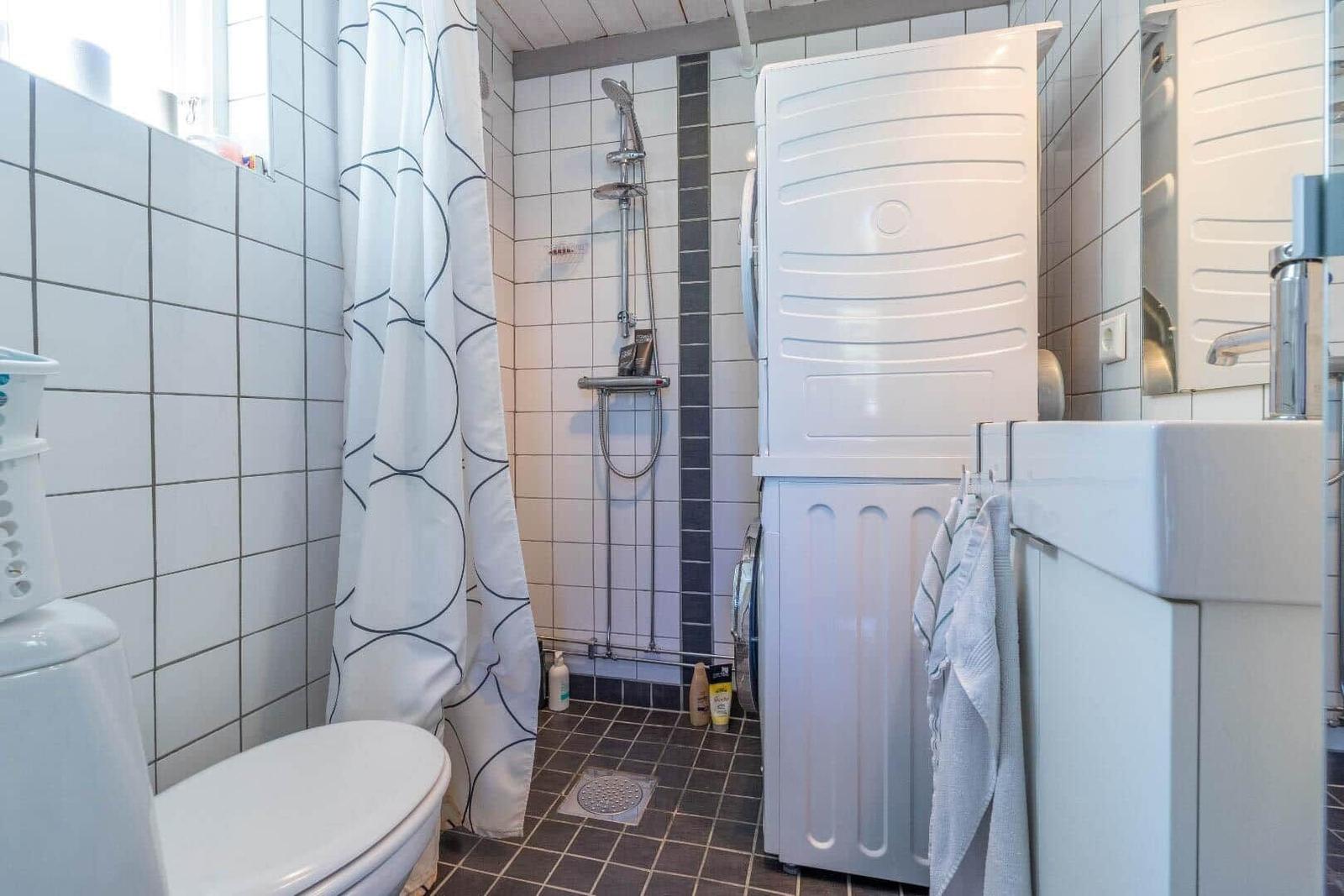 Badezimmer mit Dusche, Waschmaschine und Toilette.