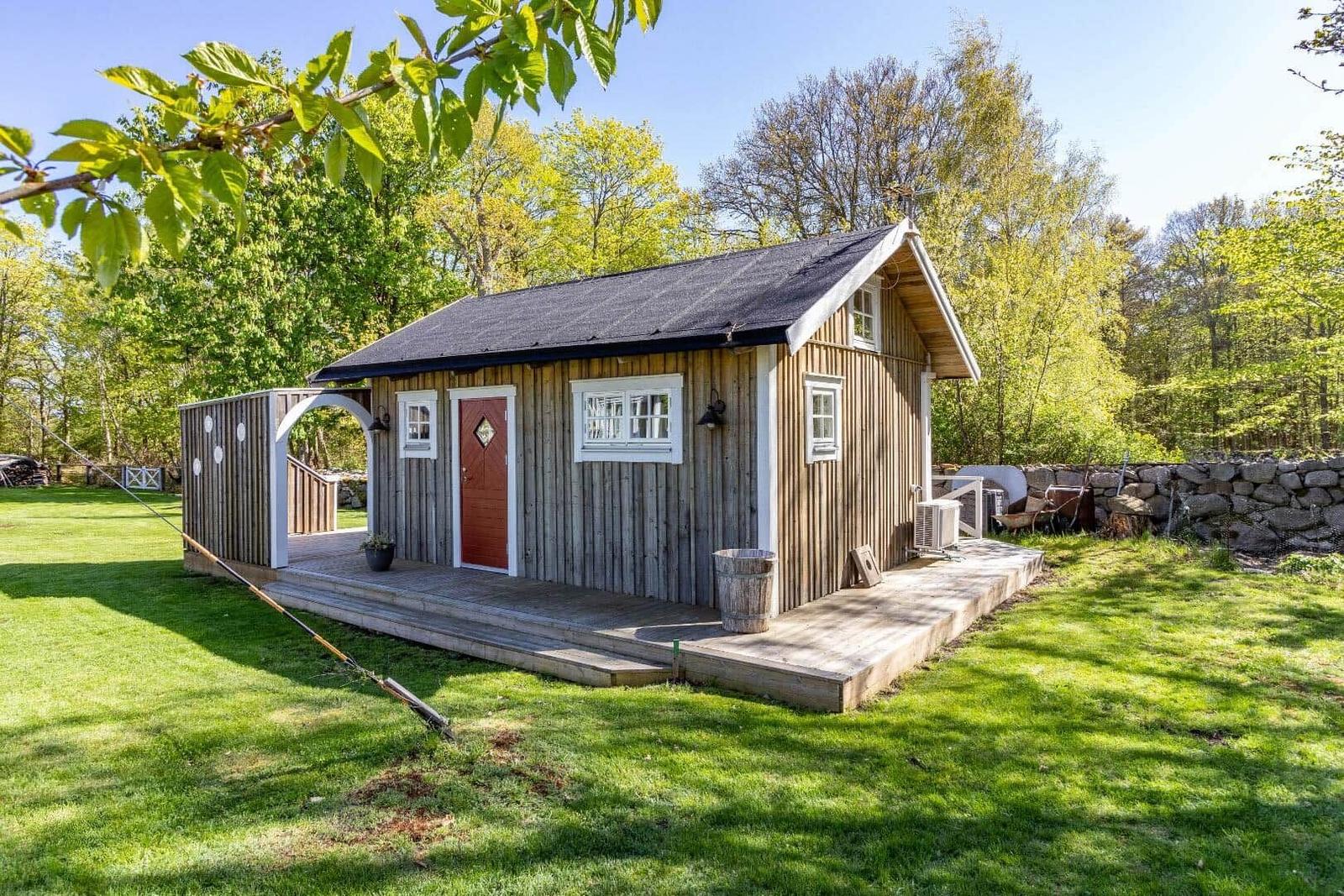 Holzhaus mit roter Tür und Holzveranda im Grünen