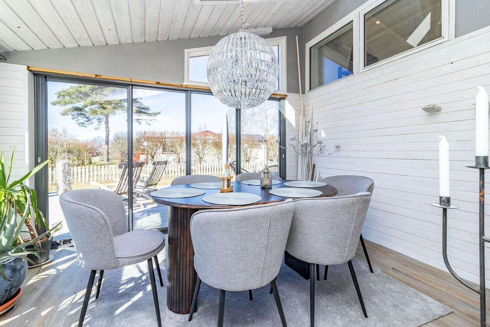 Essbereich mit runder Tisch, grauen Stühlen und Glasfront zur Terrasse.