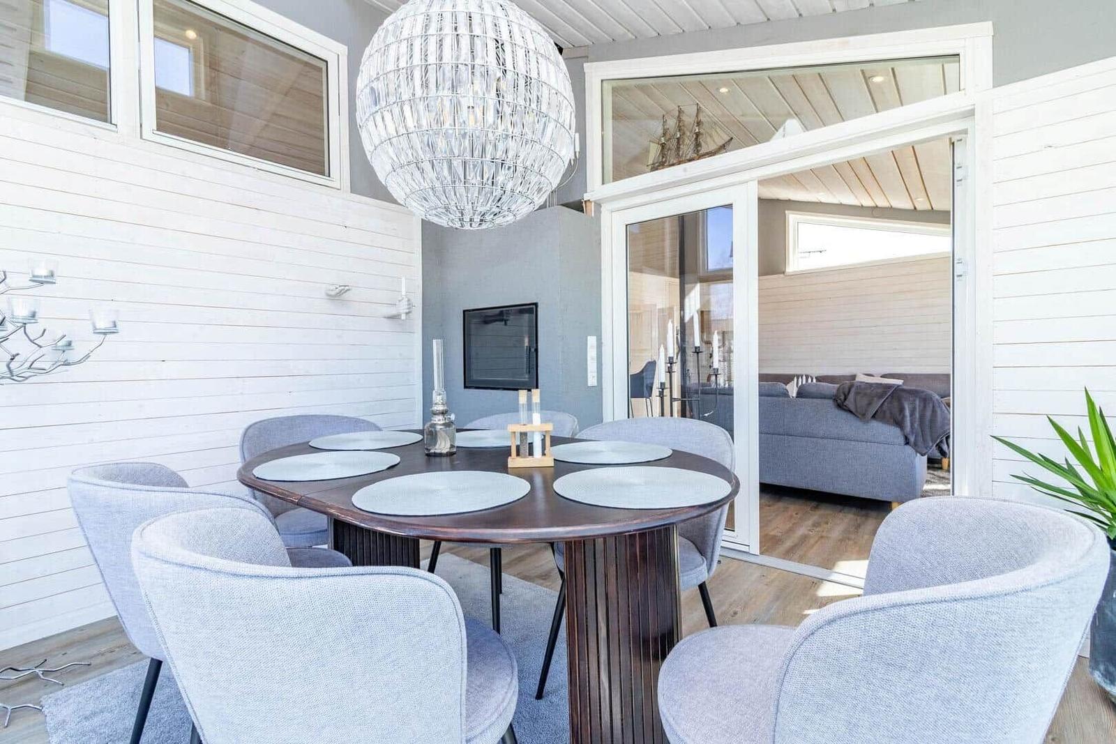 Essbereich mit runden Tisch und Stühlen, Glaswand zum Wohnzimmer, Deckenleuchte.