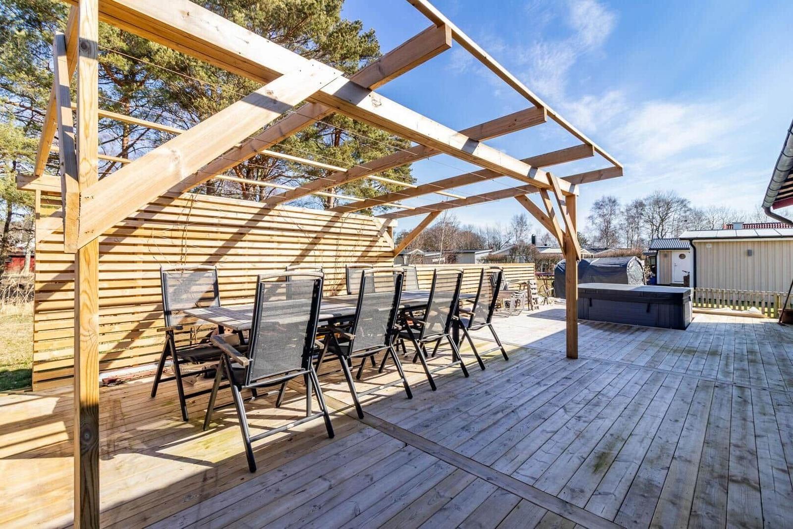 Holzterrasse mit Pavillon, Sitzgruppe und Whirlpool im Freien.