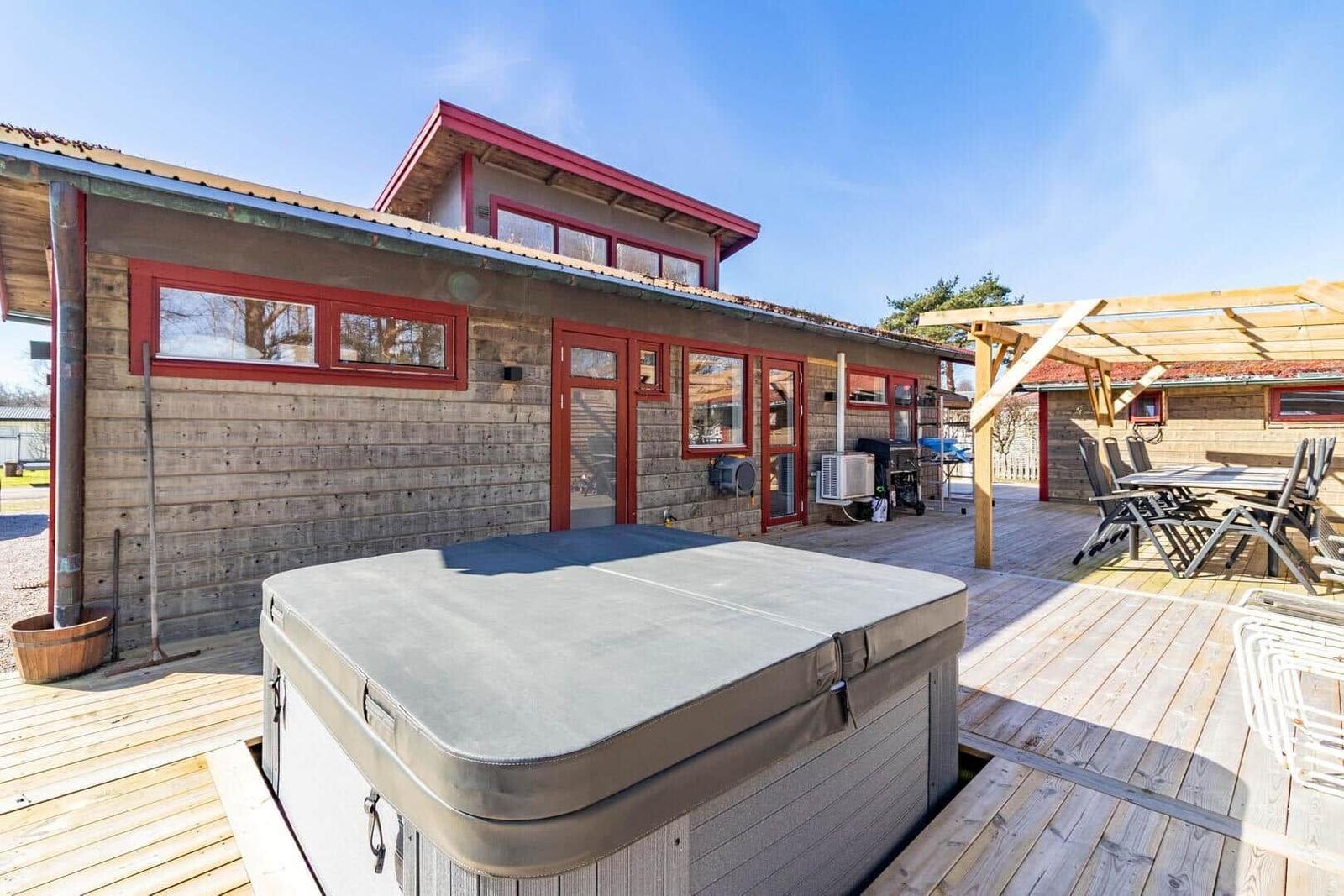 Haus mit Whirlpool, Terrasse und Sitzgelegenheiten im Freien.