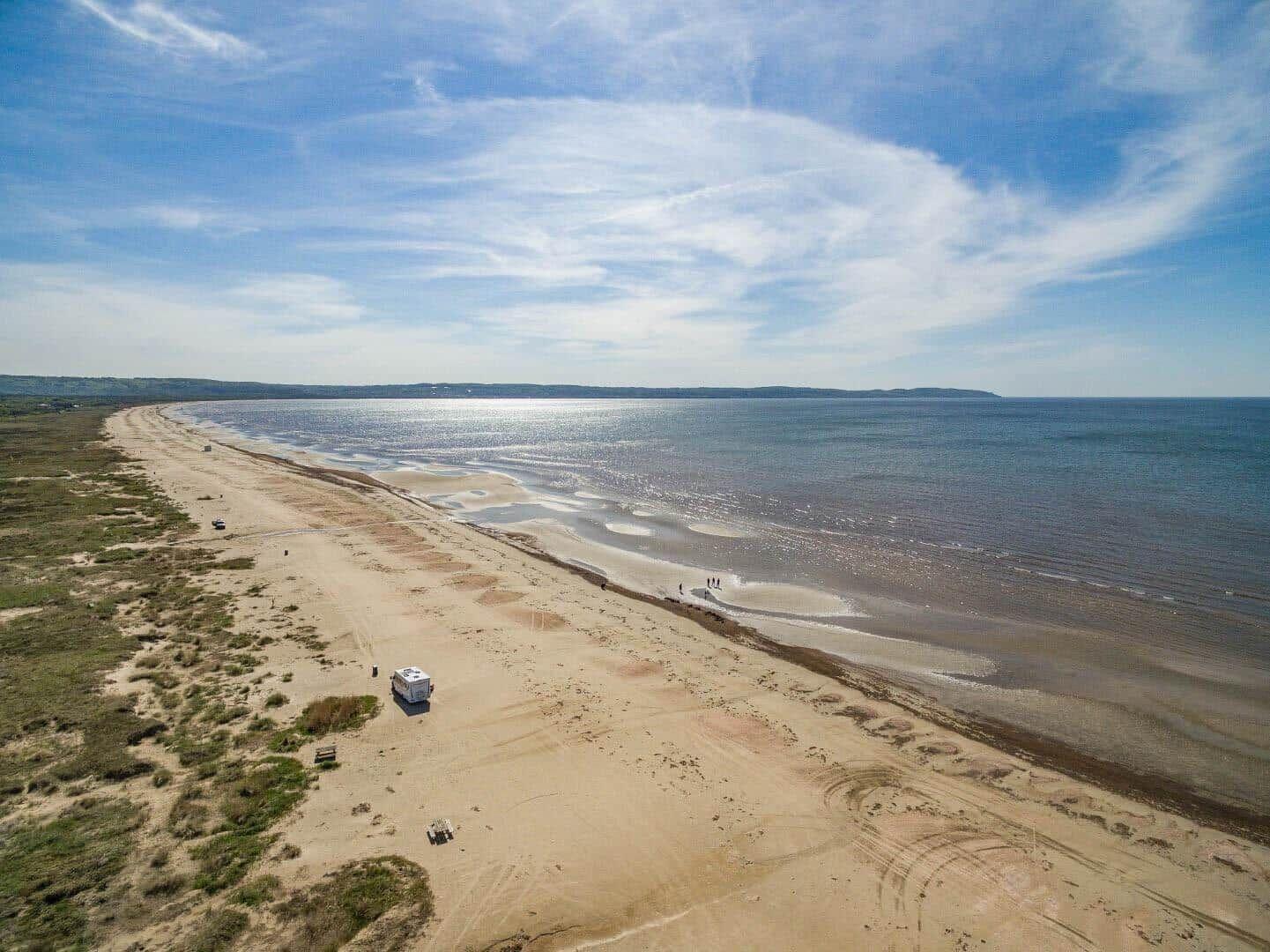 Strand mit Wohnwagen und wenigen Besuchern an der Küste.