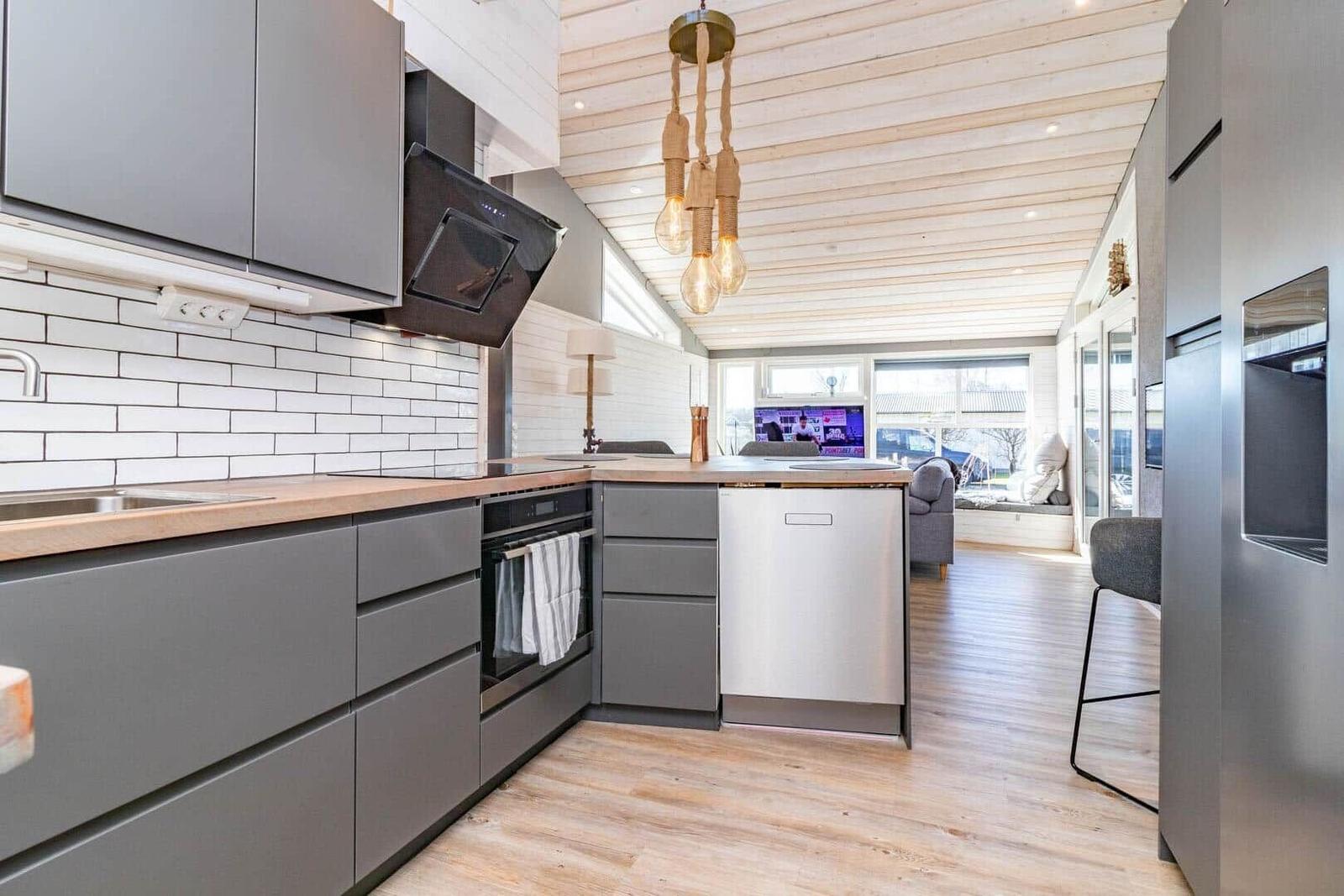 Moderne Küche mit grauen Schränken, Holzoberfläche und weißer Fliesenwand.