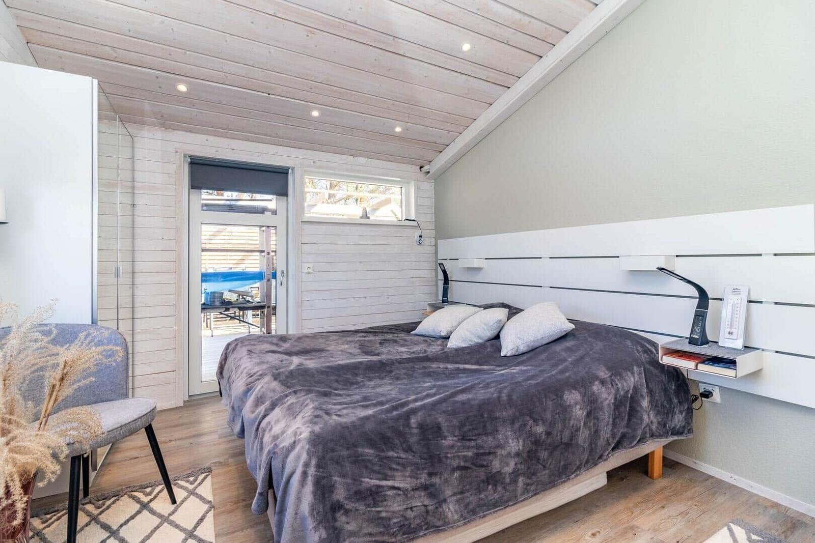 Schlafzimmer mit Bett, Nachttisch und Tür zum Balkon.