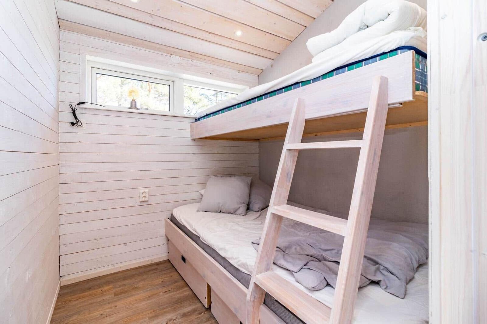 Zimmer mit Doppelstockbett, Holzwand und Fenster.
