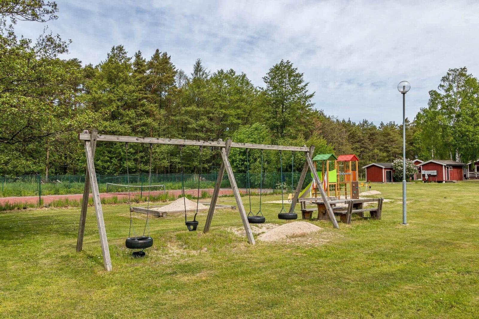 Kinderspielplatz mit Schaukel und Klettergerüst auf grünem Rasen.