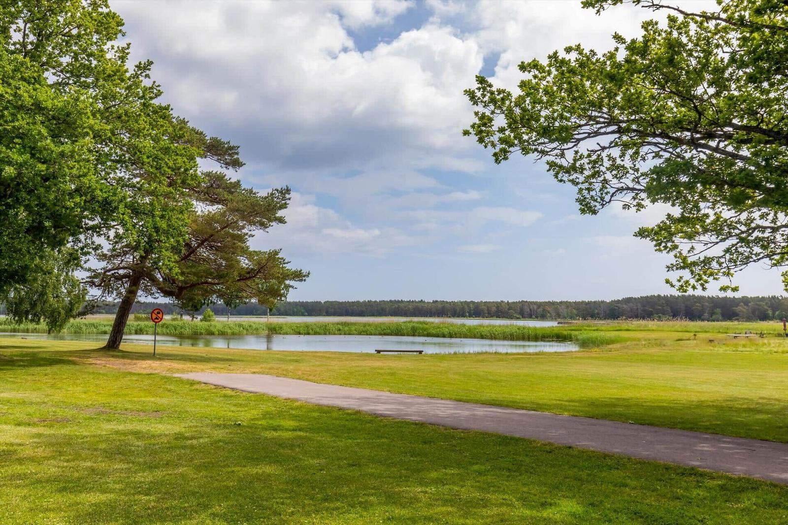 Golfplatz mit Wasserfläche und Bäumen unter blauem Himmel.