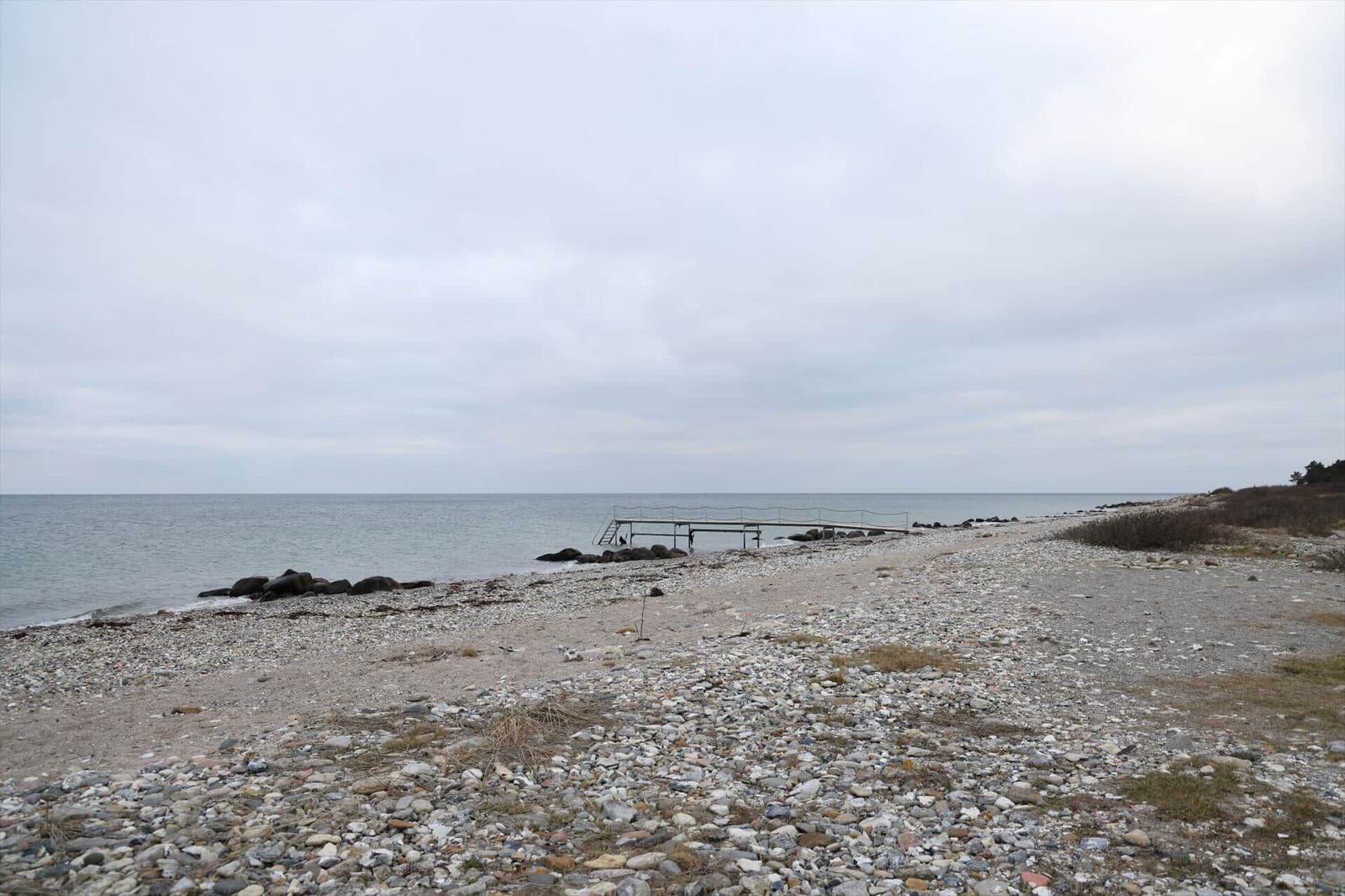 Steiniger Strand mit Bootssteg direkt am Wasser