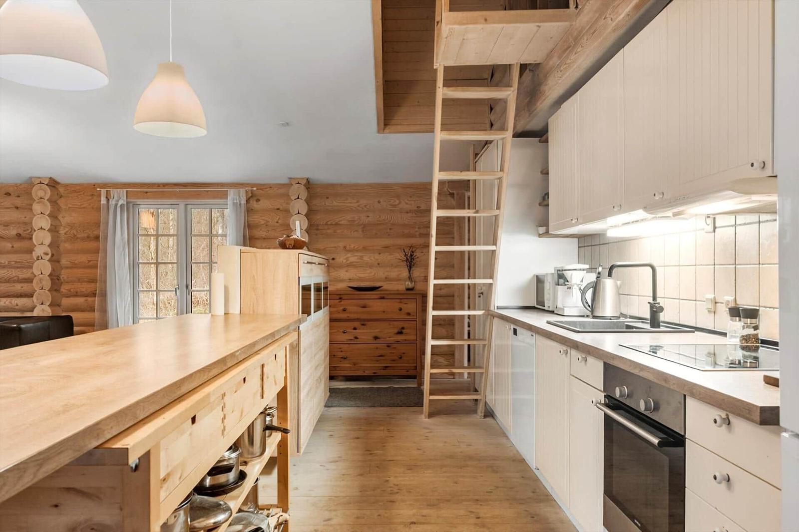 Küche mit Holzoberflächen, Kühlschrank, Herd und Treppe zum Dachboden.