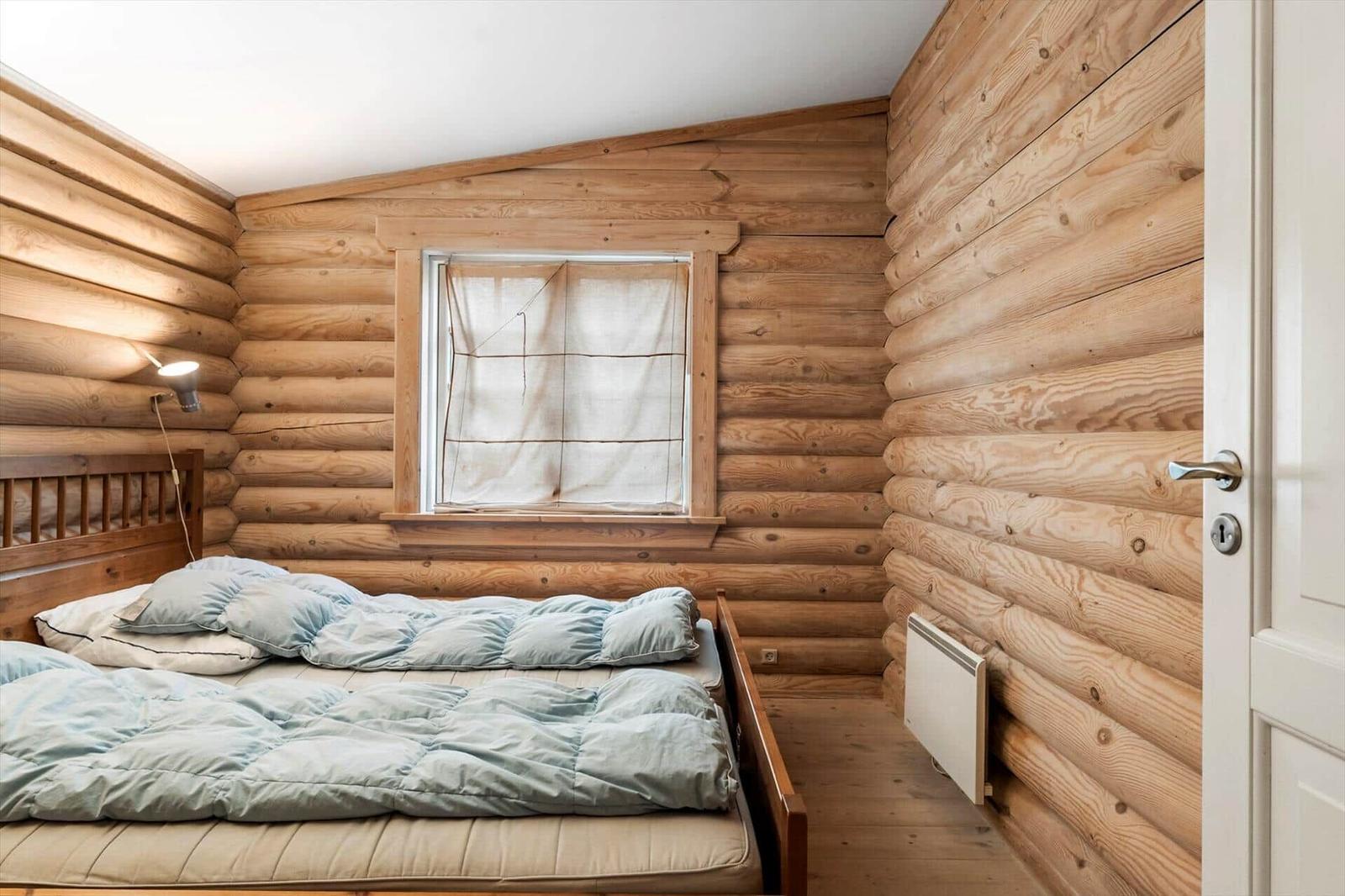 Schlafzimmer mit Holzwand, Bett und Fenster