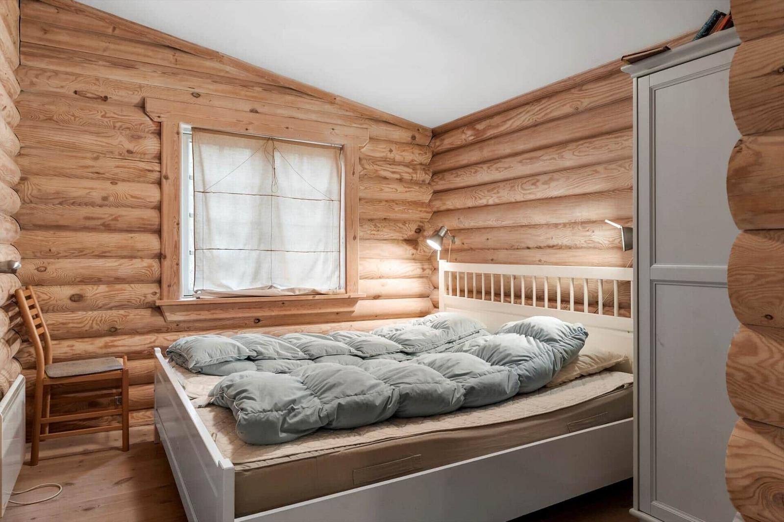 Schlafzimmer mit Holzwand, Bett, Stuhl und Kleiderschrank.