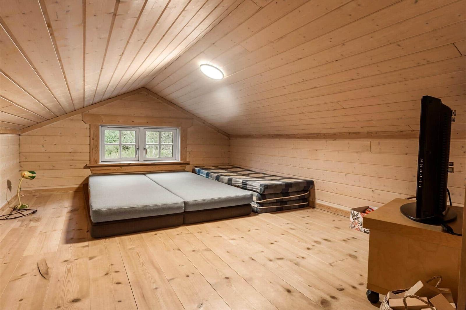 Schlafzimmer mit Holzwand, Bett und Fenster
