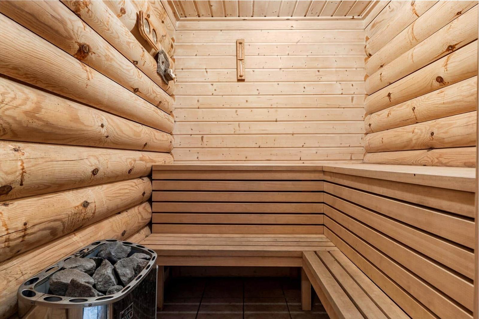 Holzsauna mit Sitzbänken und Steinbehälter.