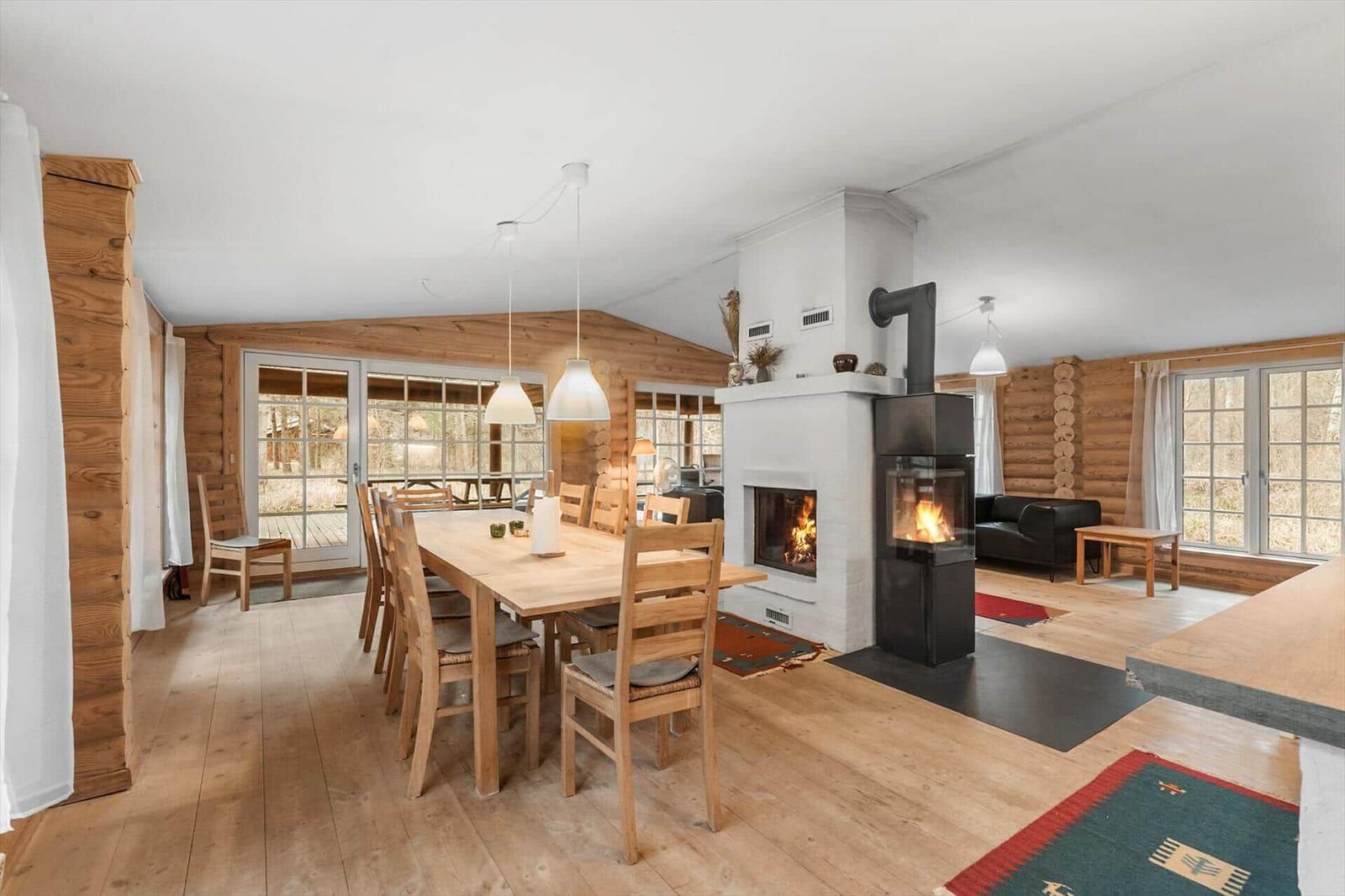 Esszimmer mit Holztisch, Kamin und Sitzbereich. Holzwände und -boden.