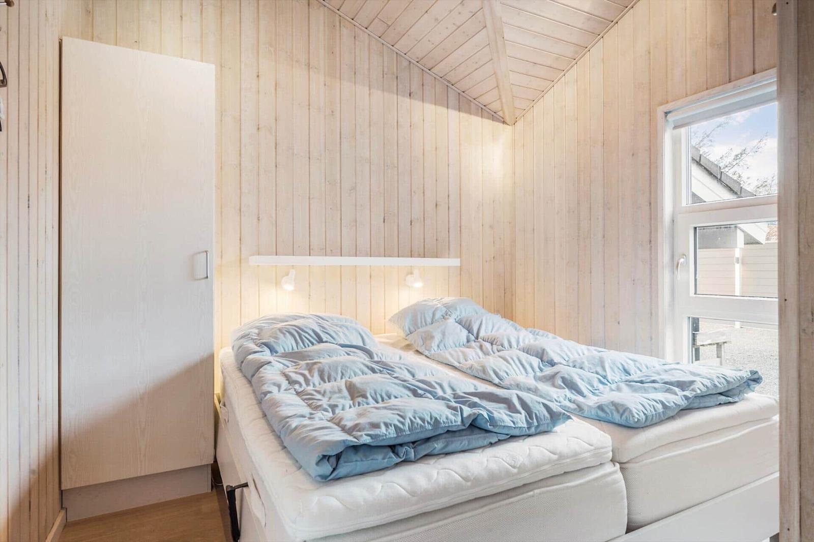 Bedroom with double bed, wooden walls, and window.