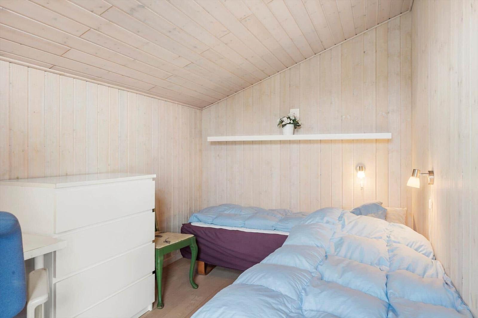 Bedroom with bed, dresser, and wood-paneled walls.