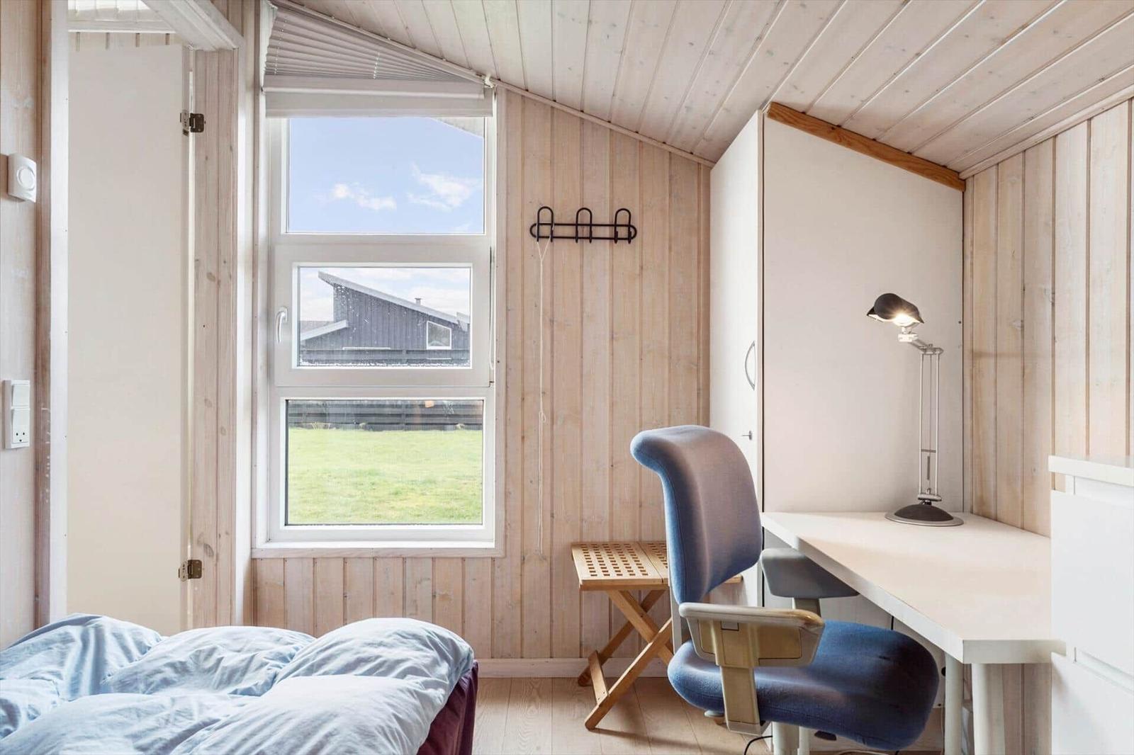 Room with desk, chair, and window overlooking green area