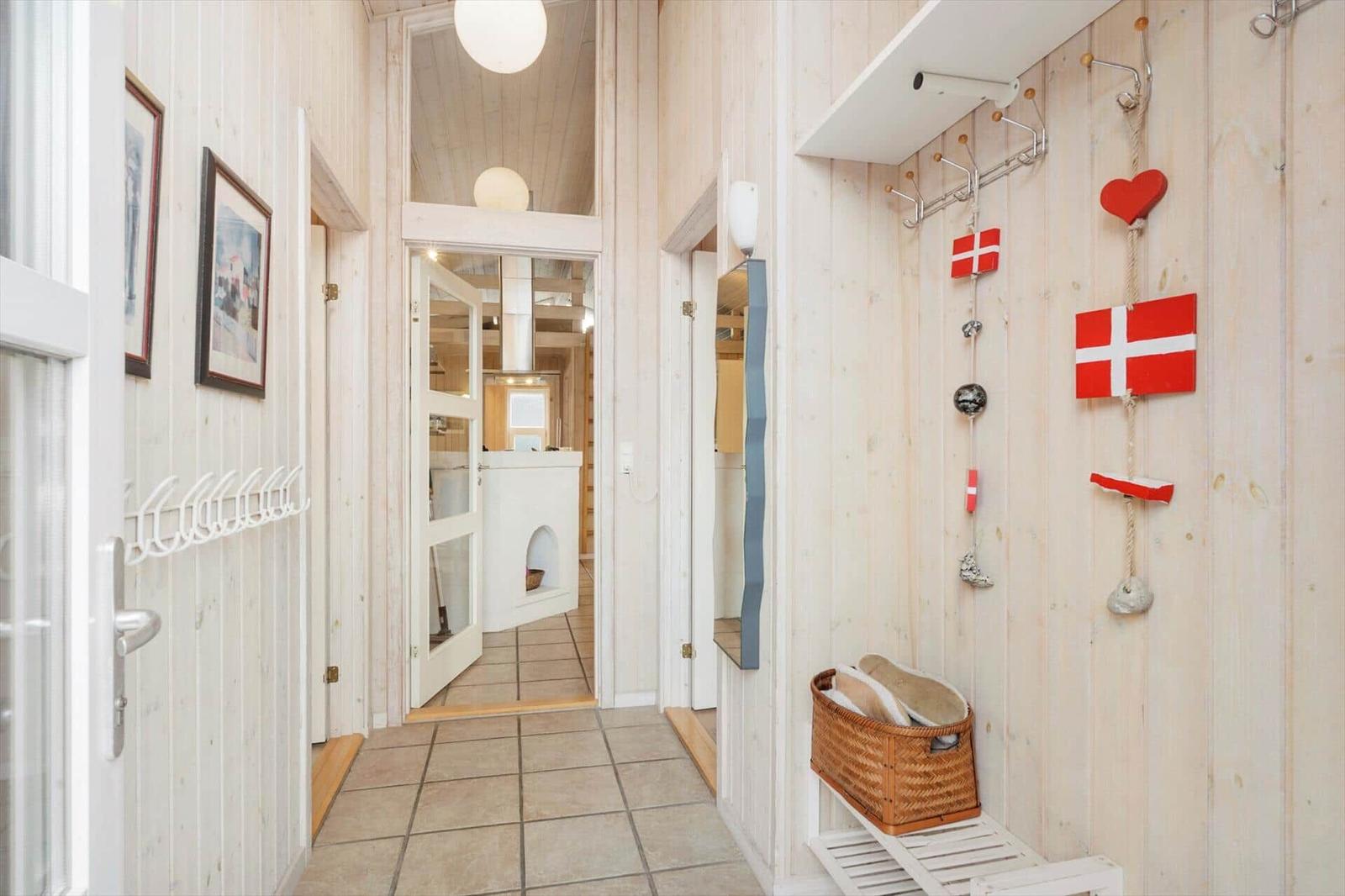 Hallway with wooden walls, coat rack, and Danish flags on the wall.