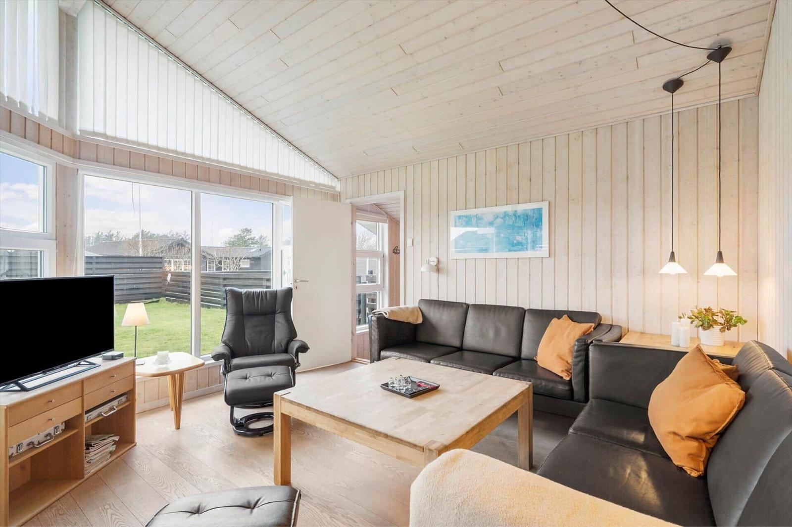Living room with wooden walls, sofa, TV, and large window.