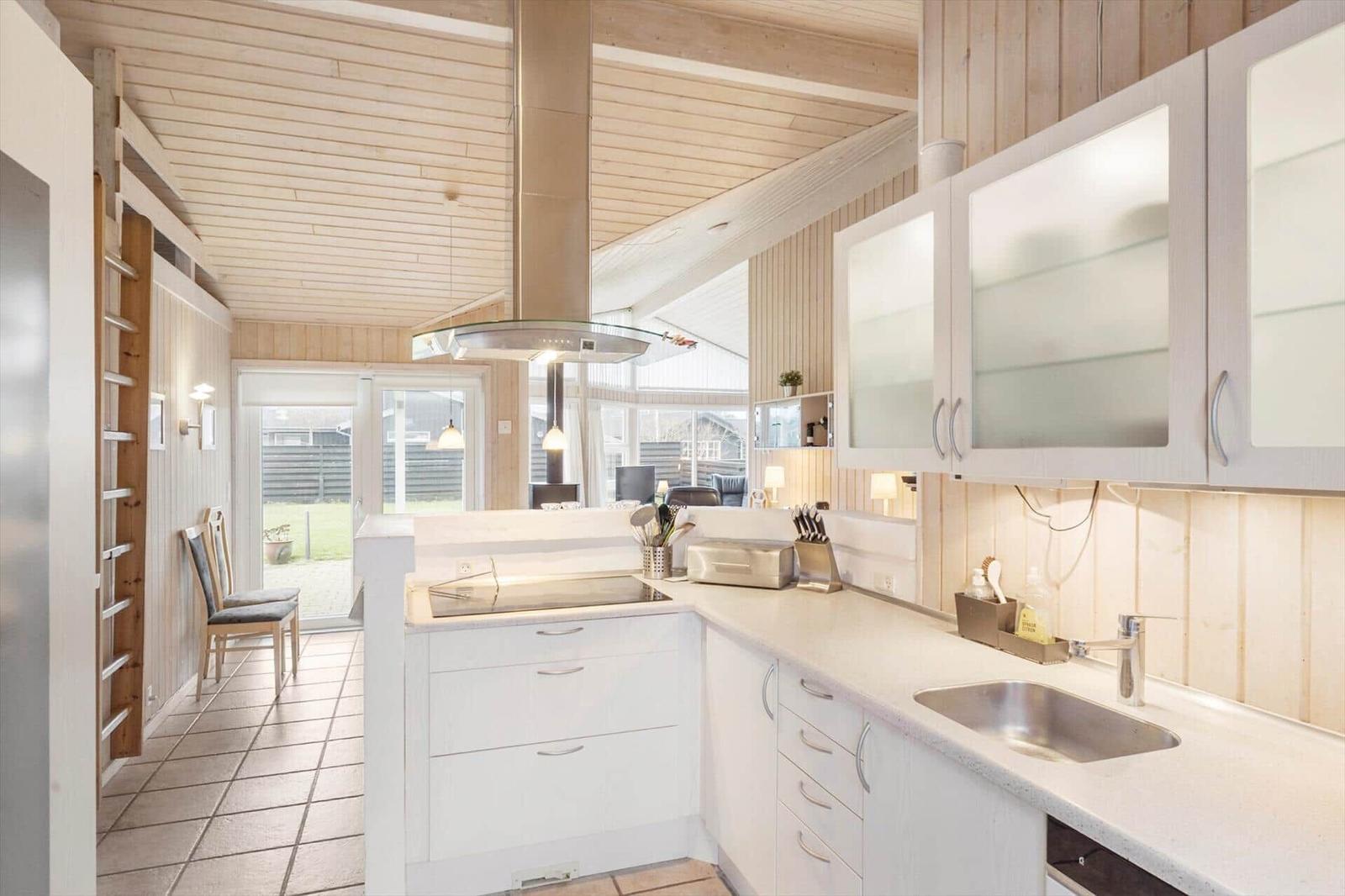 Kitchen with white cabinets, stainless steel sink, and wood paneling.