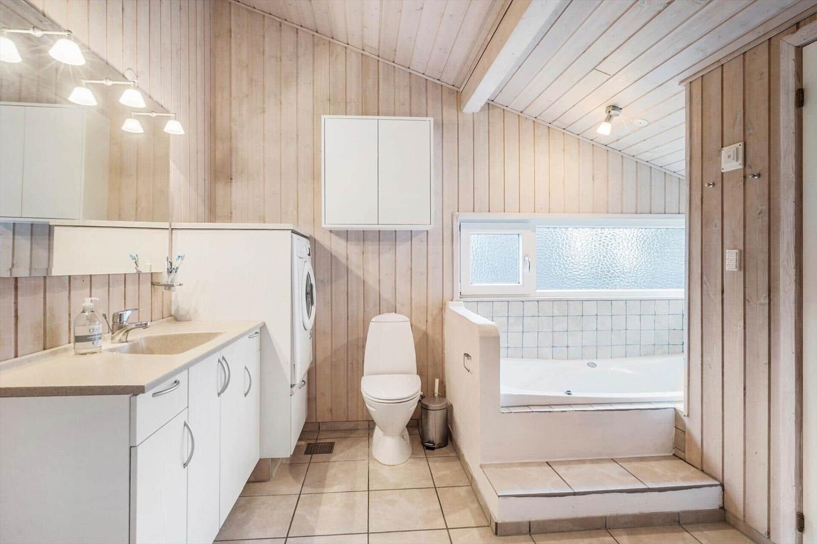 Bathroom with bathtub, toilet, and washing machine.