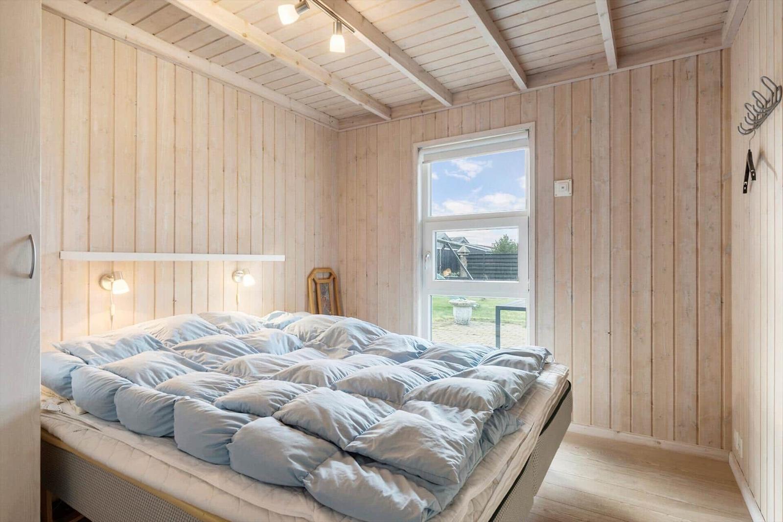 Bedroom with wooden walls, bed, and window