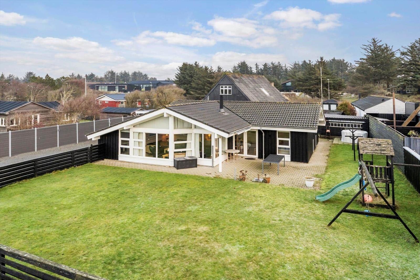 House with large garden, playground, and terrace. View of surrounding houses and trees.