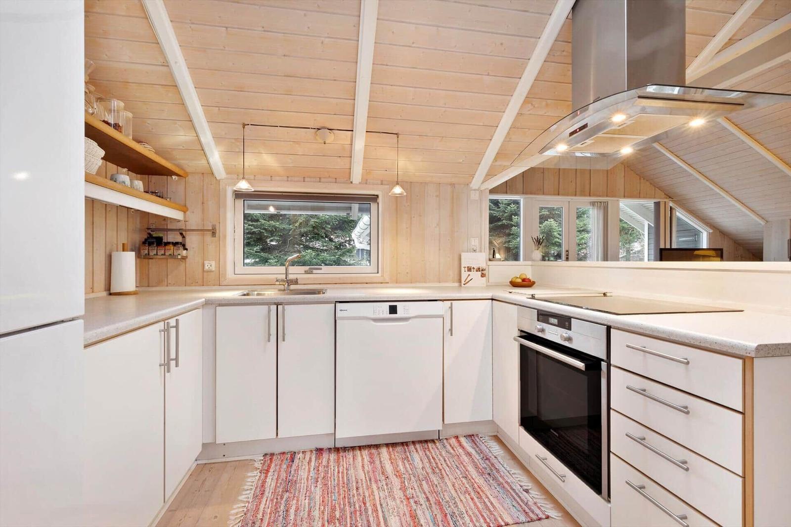 Kitchen with white cabinets, stainless steel appliances, and wooden ceiling.