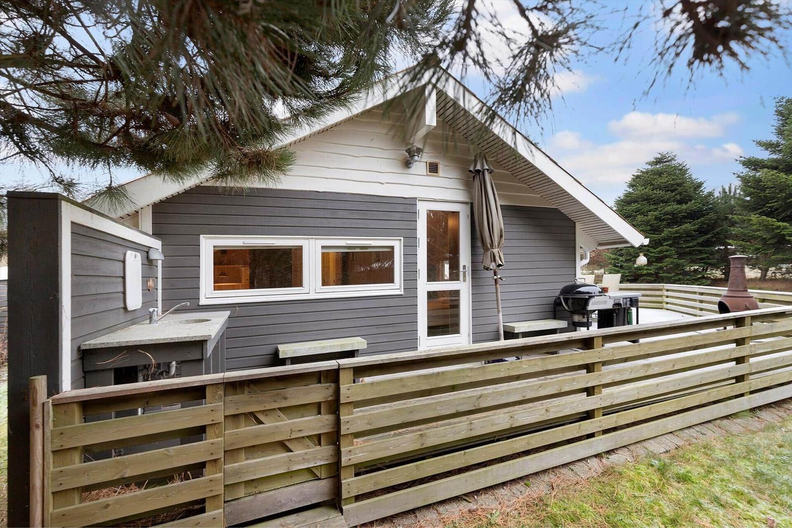 A small house with a balcony, grill, and outdoor sink.