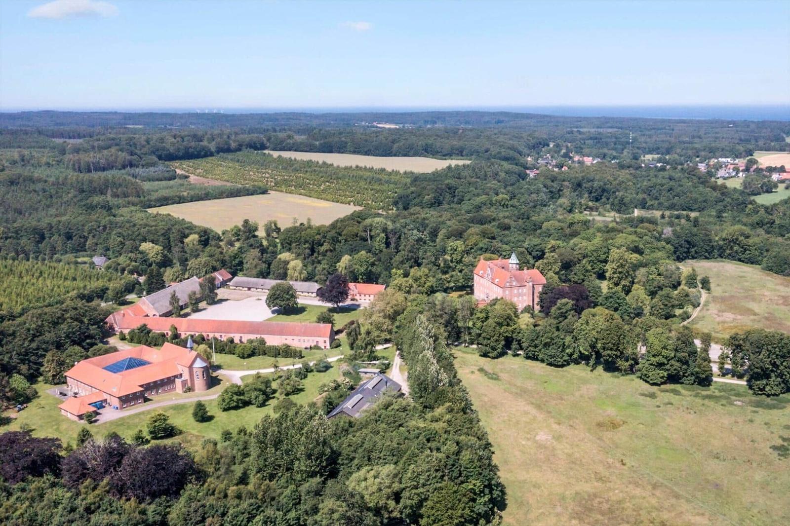 Rural property with multiple buildings and surrounding forests and fields.